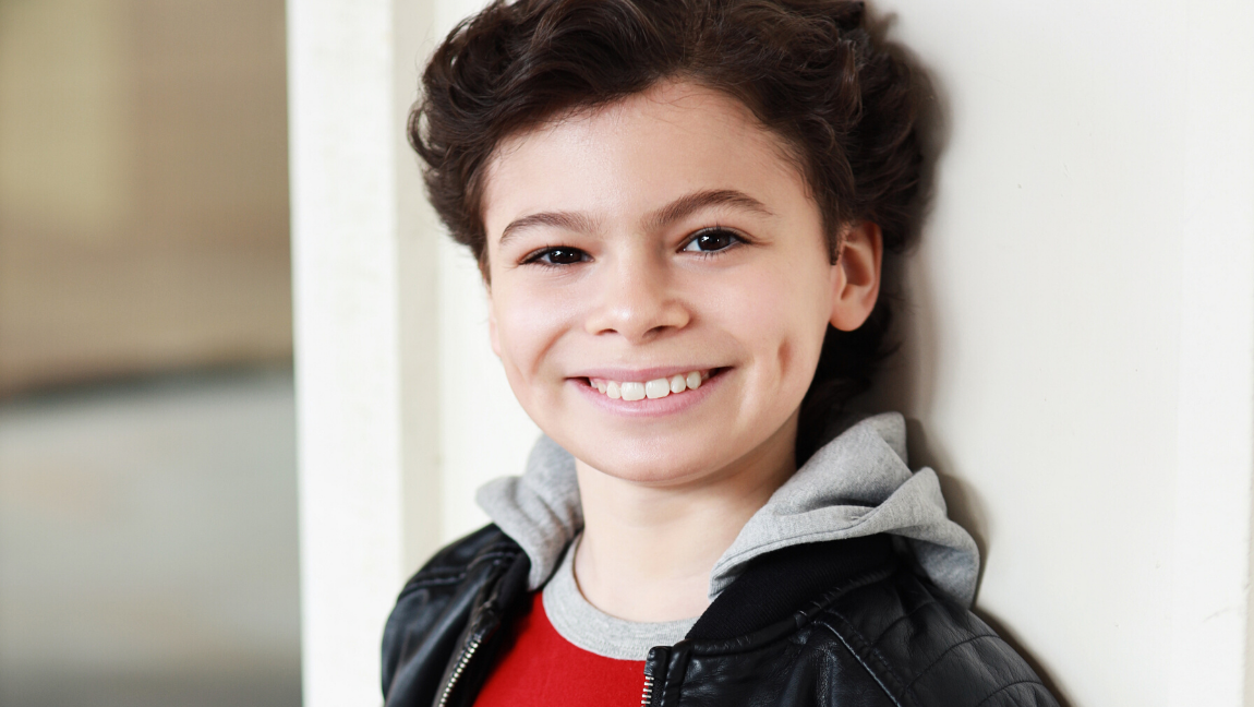 Boy smiles and looks ahead.