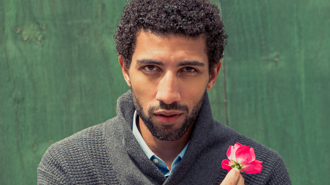 Man looks ahead and holds a flower.